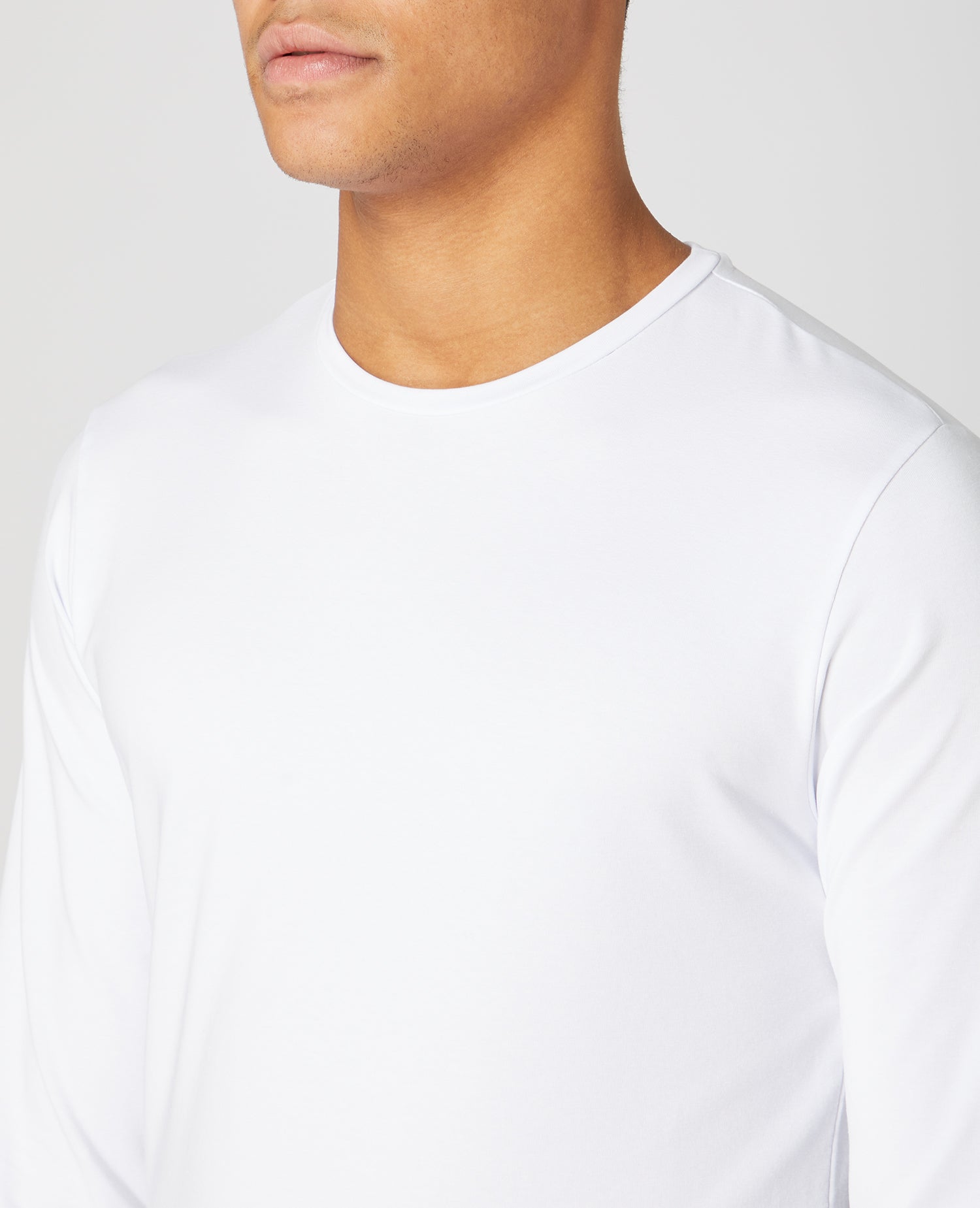 Man wearing a white Tapered Fit Cotton-Stretch Long Sleeve T-Shirt