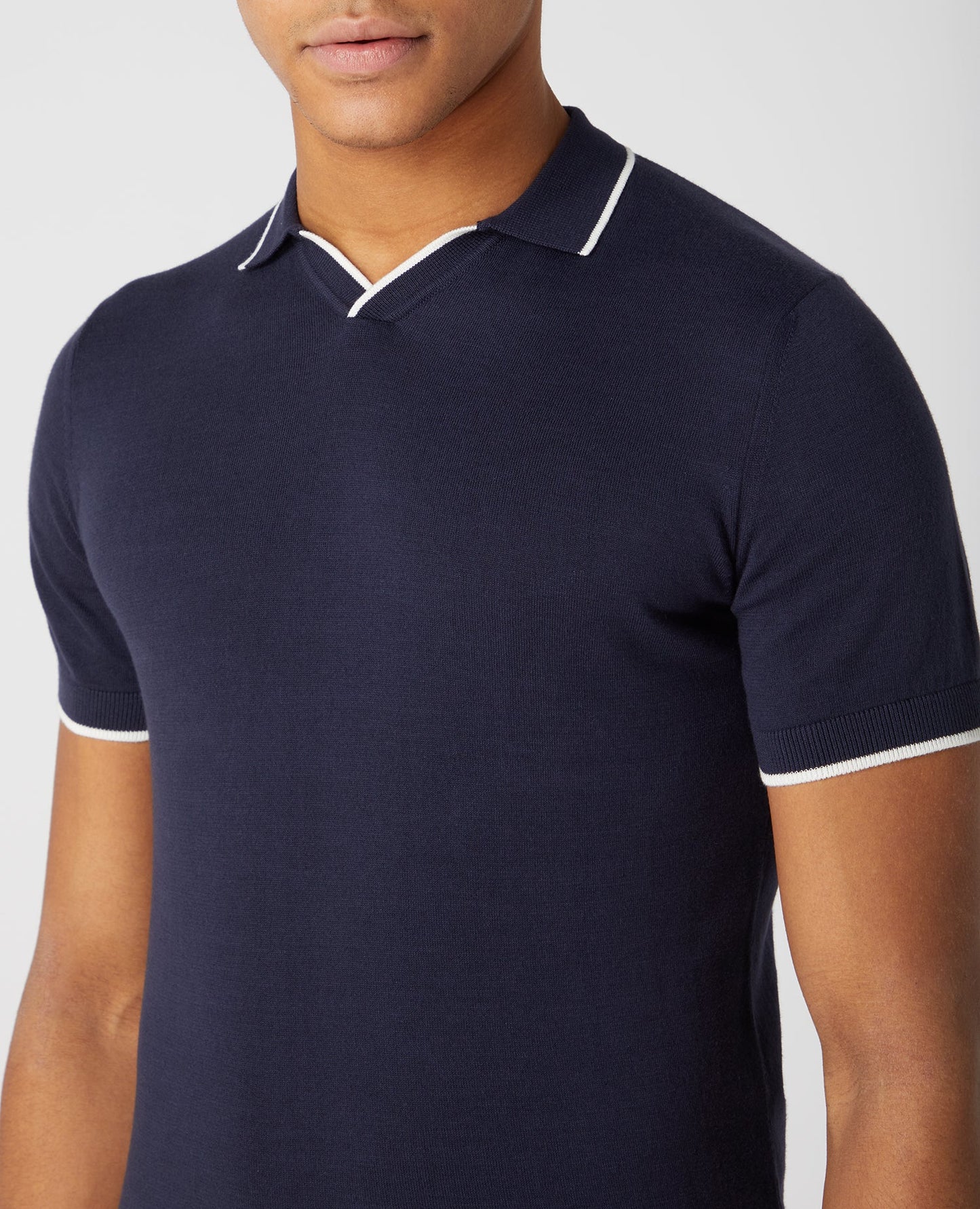Man wearing a navy Slim Fit Knitted Cotton Short Sleeve Polo Shirt