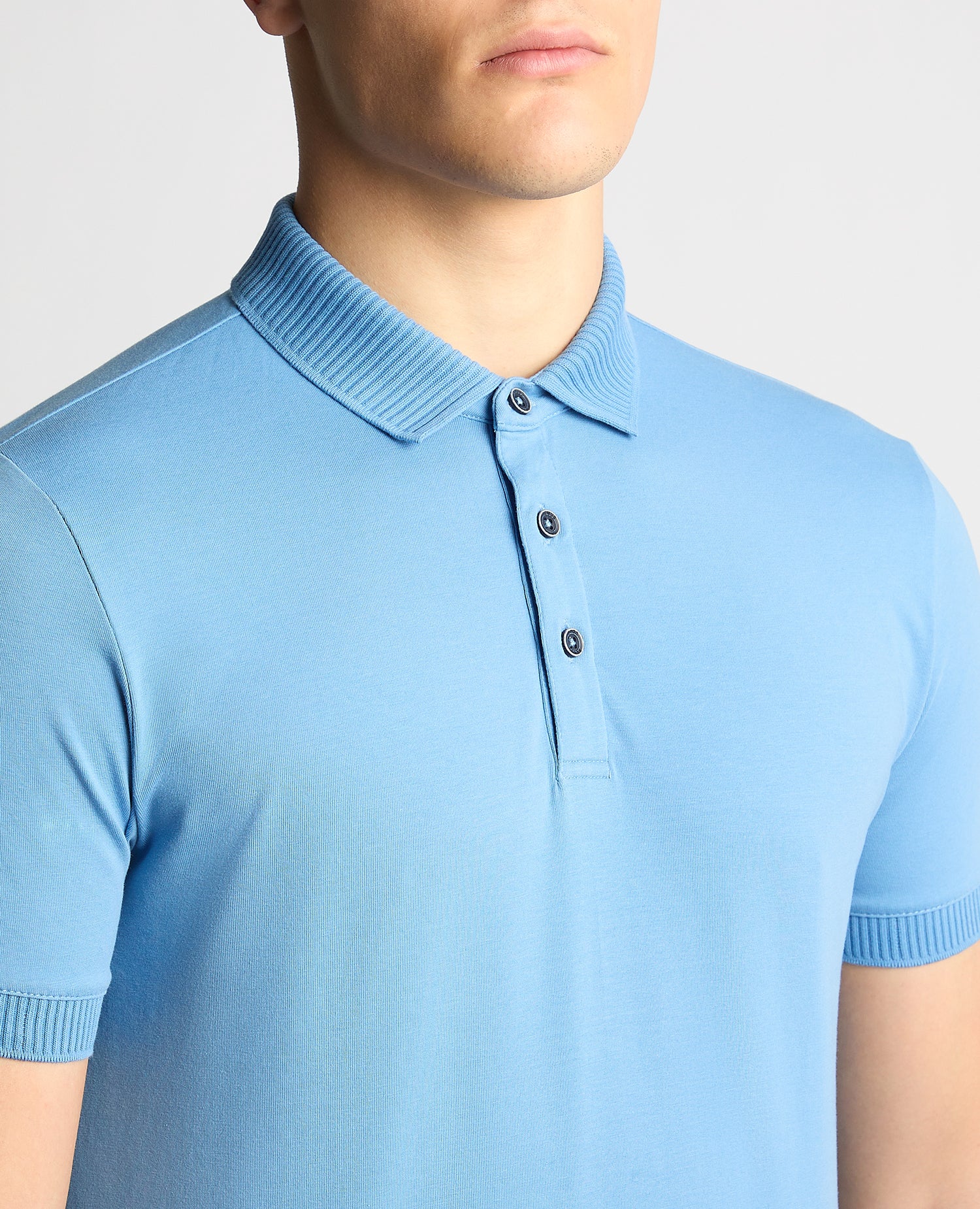 Man wearing a blue Tapered Fit Cotton-Stretch Polo Shirt
