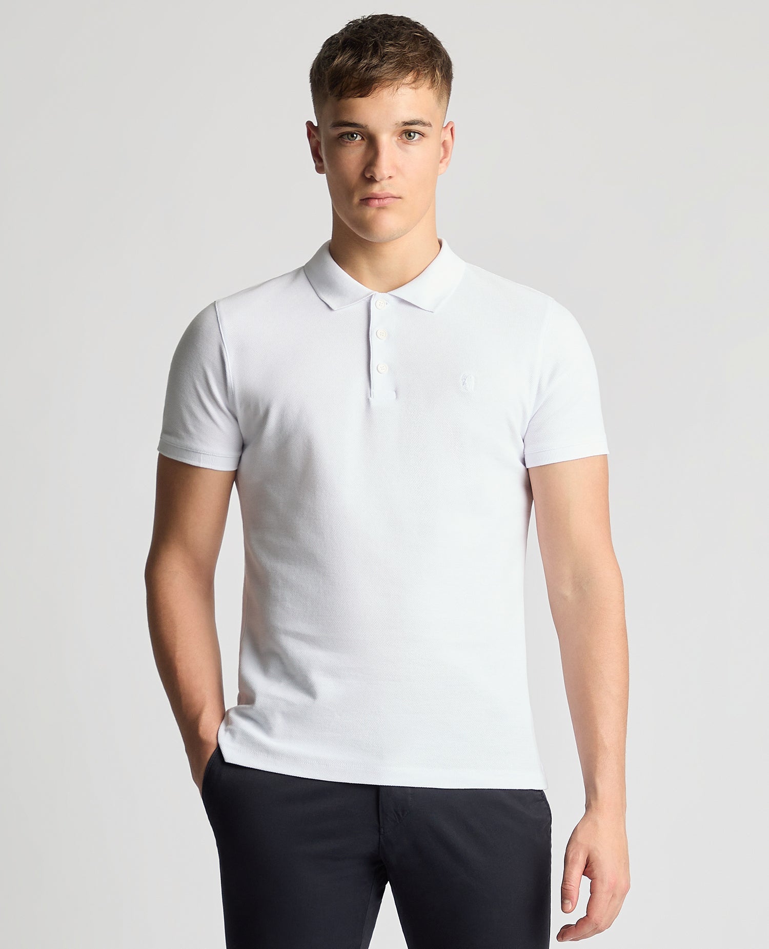 Man wearing a white Tapered Fit Cotton Pique Polo Shirt