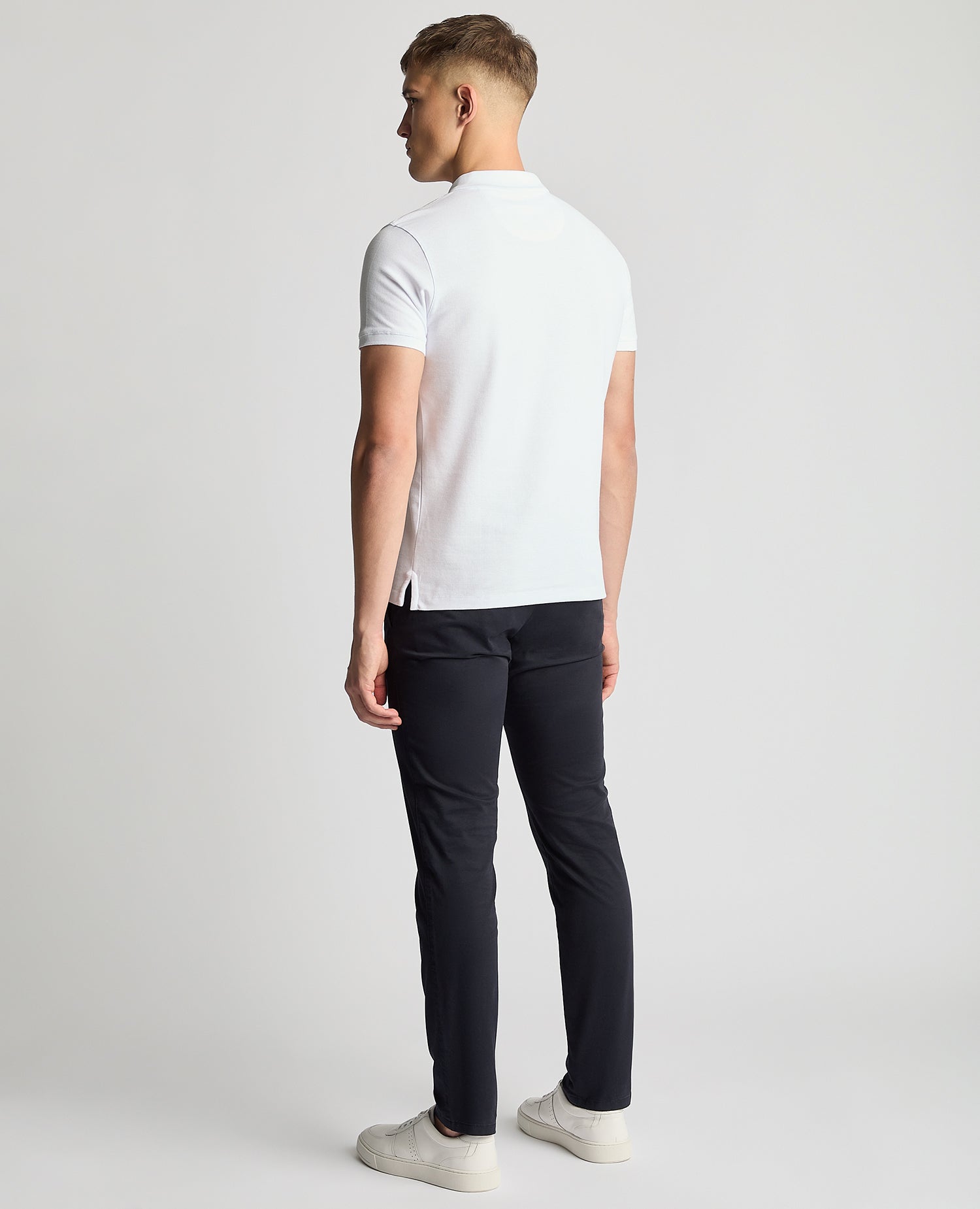 Man wearing a white Tapered Fit Cotton Pique Polo Shirt