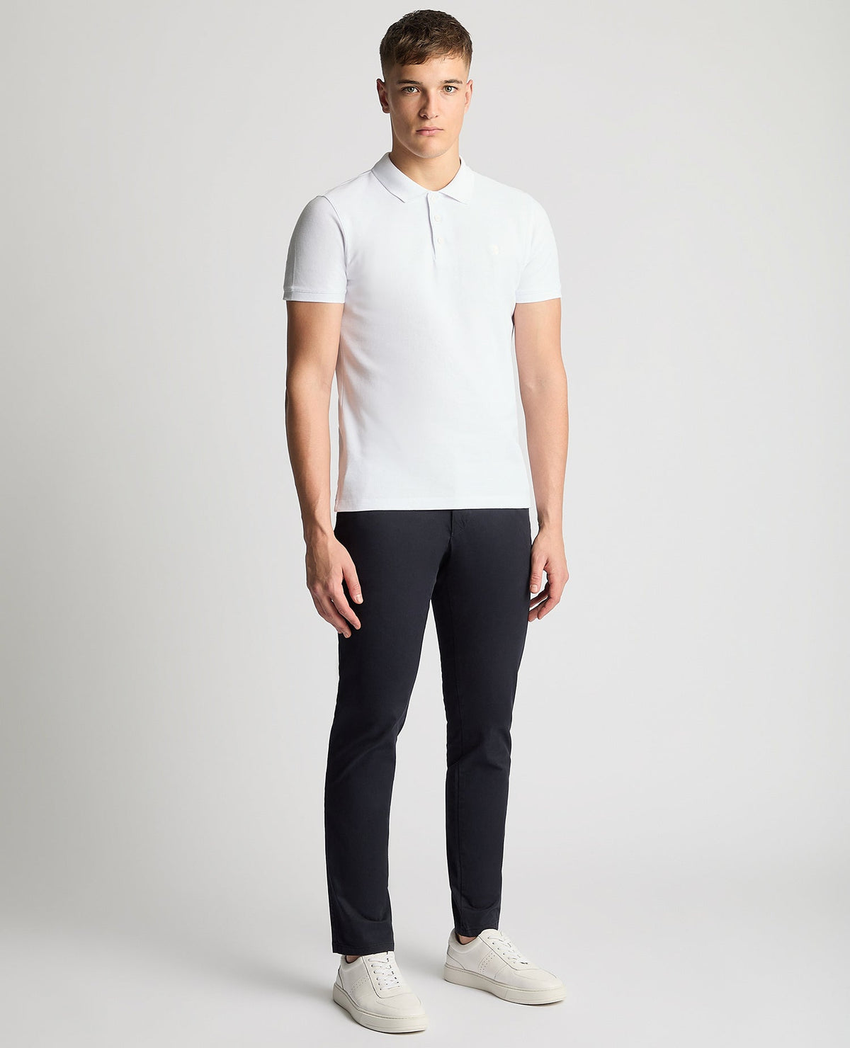 Man wearing a white Tapered Fit Cotton Pique Polo Shirt