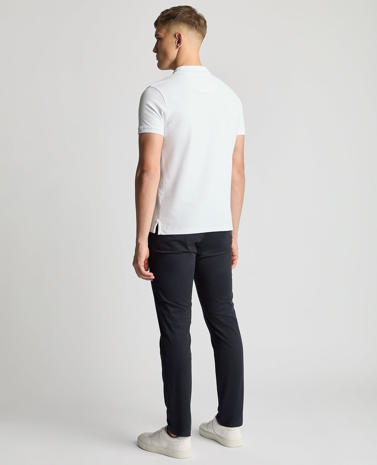 Man wearing a white Tapered Fit Cotton Pique Polo Shirt