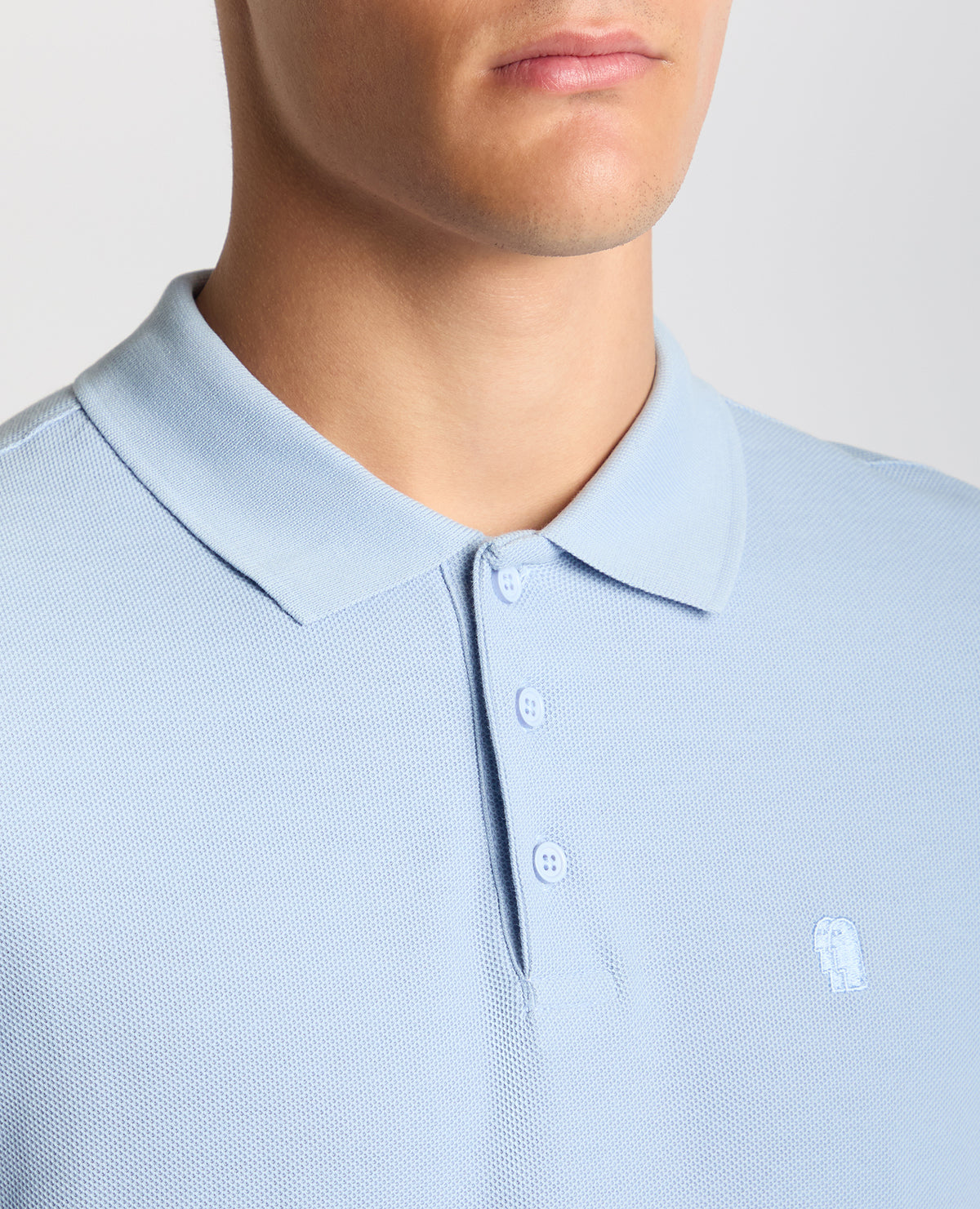 Man wearing a blue Tapered Fit Cotton Pique Polo Shirt