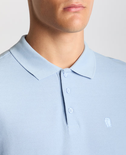 Man wearing a blue Tapered Fit Cotton Pique Polo Shirt