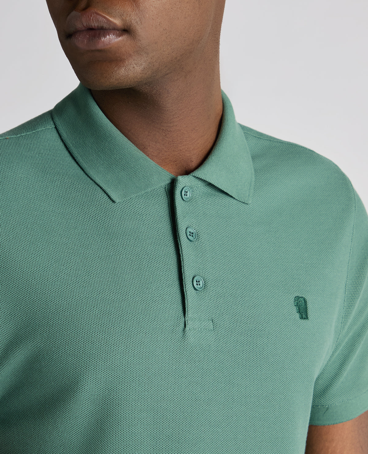 Man wearing a green Tapered Fit Cotton Pique Polo Shirt